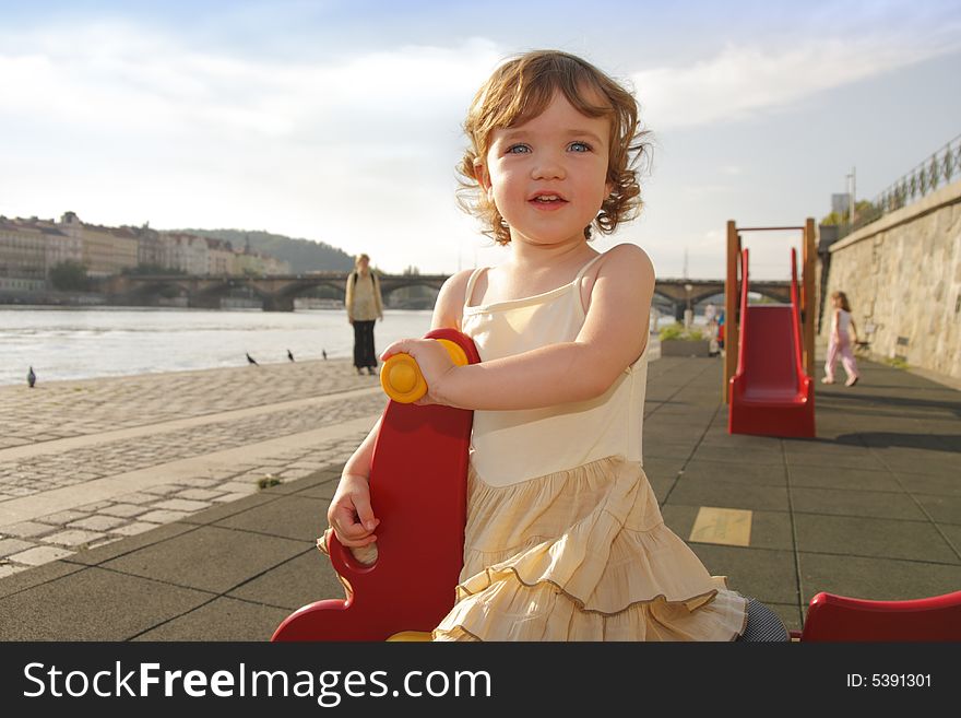 A playful little girl is rocking on the playground. A playful little girl is rocking on the playground.