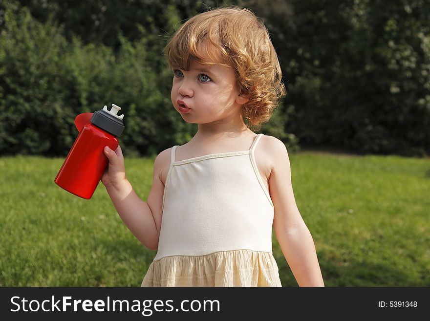 A little girl with a red flask in her hand.