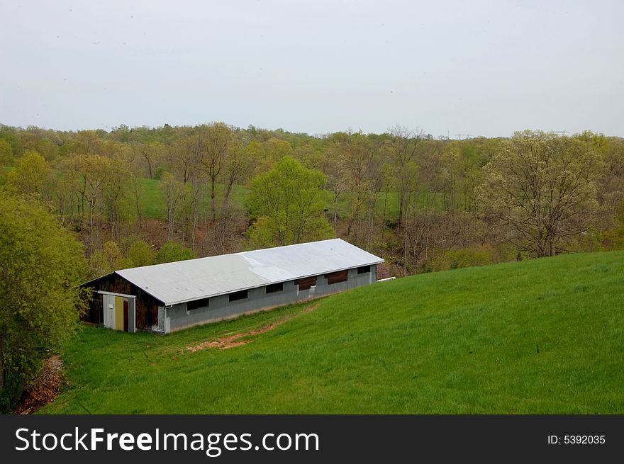 This is a storage barn on a hillside in West Virginia. Lots of green grass and other early spring colors.