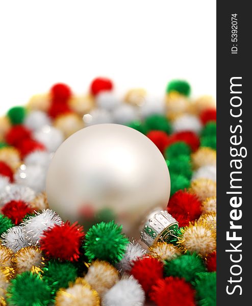 Silver Christmas bauble resting on colorful puff ball decorations over a white background. Silver Christmas bauble resting on colorful puff ball decorations over a white background