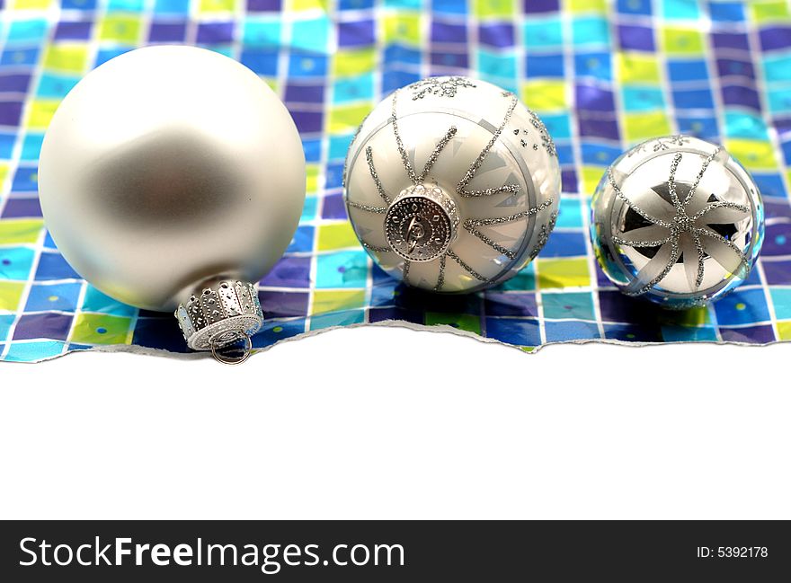 Holiday decoration ornaments resting over wrinkled used torn wrapping paper on white background