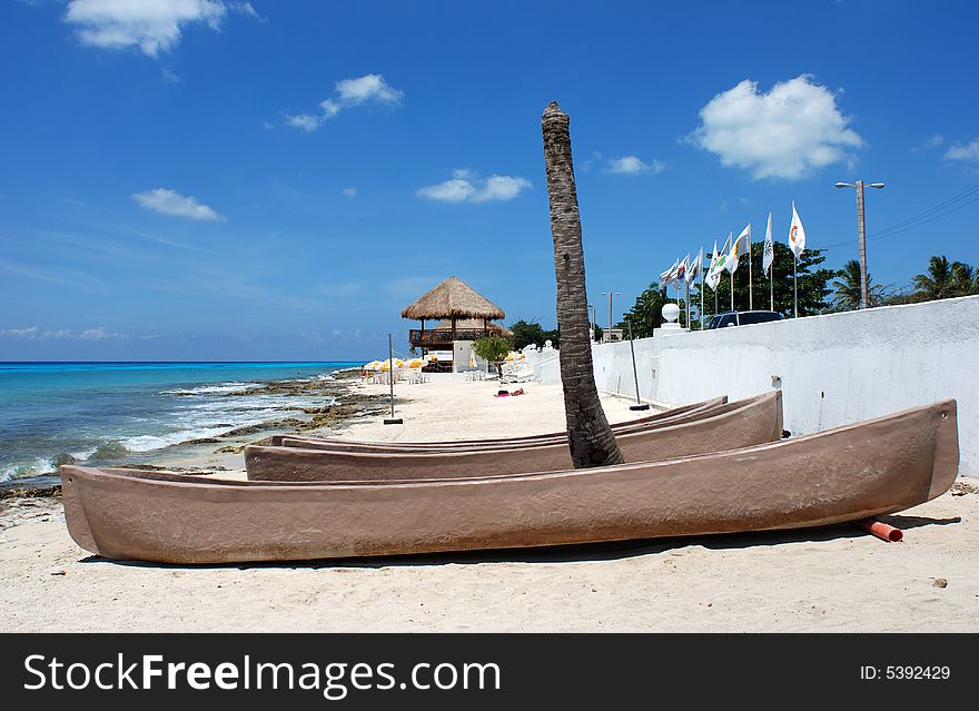 Canoes under the broken palm on San Miguel town beach (Cozumel island, Mexico).
