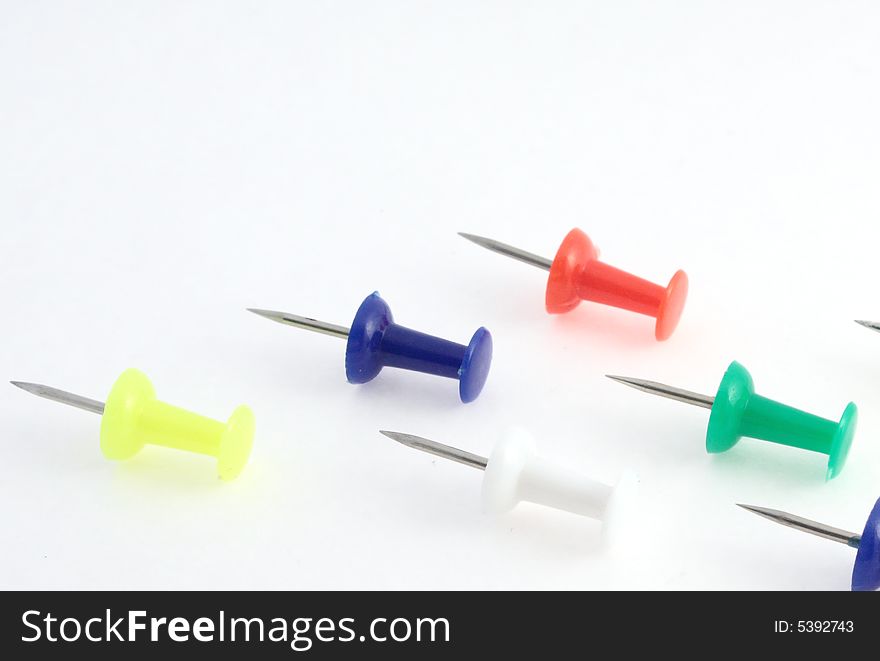 Thumbtack ordered in one direction white, dark blue, red yellow and green.