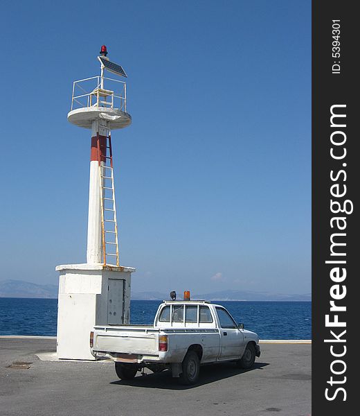 White lighthouse and a small car on the seaside in harbour of the island Kos in Greece