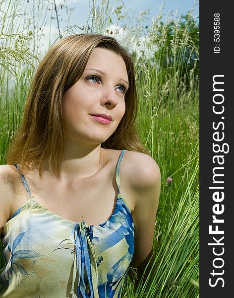 Young romantic girl sitting in tall grass