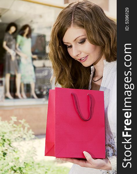Woman with shopping bag looking what she had purchased. Woman with shopping bag looking what she had purchased