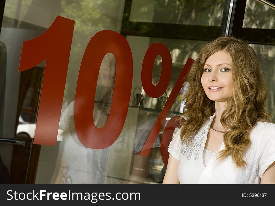 Pretty woman standing near shop window with 10% discount sign. Pretty woman standing near shop window with 10% discount sign