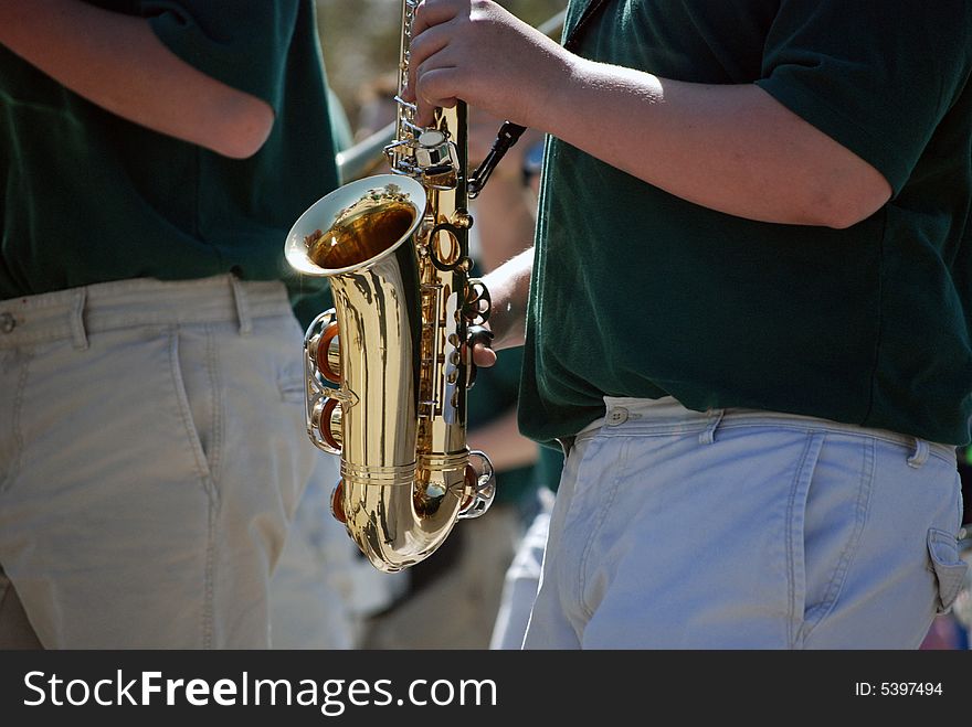 Band member playing the saxaphone in a parade. Band member playing the saxaphone in a parade.