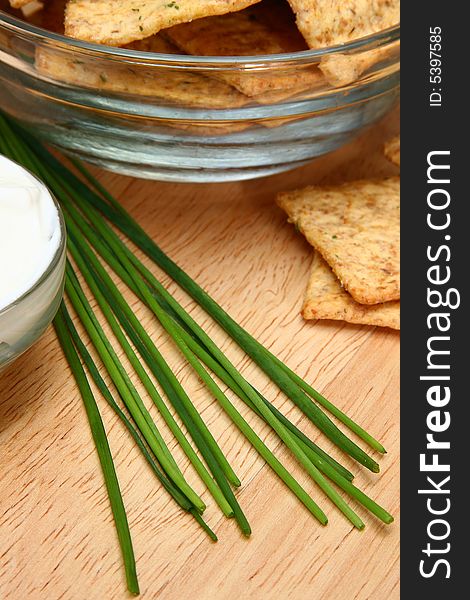 Focus on chives laying between crackers and sour cream. Focus on chives laying between crackers and sour cream.