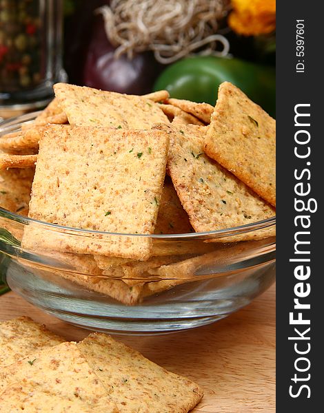 Square sour cream and chive flavored crackers in glass bowl on cutting board in kitchen or resturant.