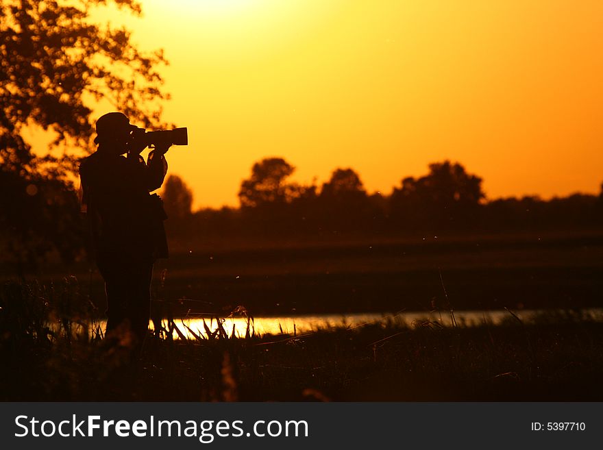 Silhouette of the photograper at  sunset sky