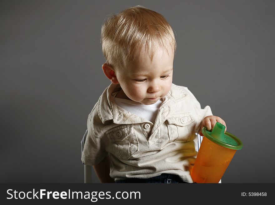 Boy sitting on little chair holding his cup of juice. Boy sitting on little chair holding his cup of juice.