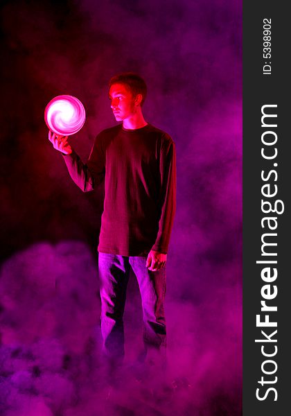 Teenage boy holding a swirling orb in the pink and purple fog. Teenage boy holding a swirling orb in the pink and purple fog.