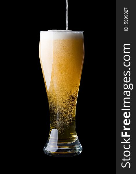 Fresh foamy beer in a glass on a black background.