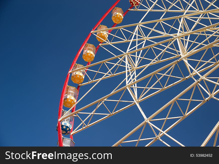 Atraktsion Ferris wheel against a blue sky with clouds. Atraktsion Ferris wheel against a blue sky with clouds
