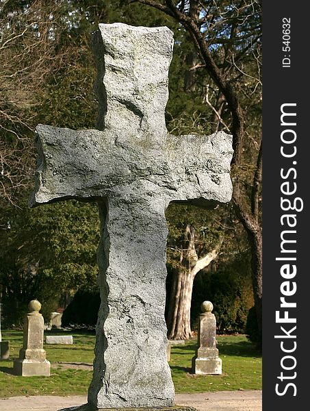 An old stone carved cross in a cemetery. An old stone carved cross in a cemetery.