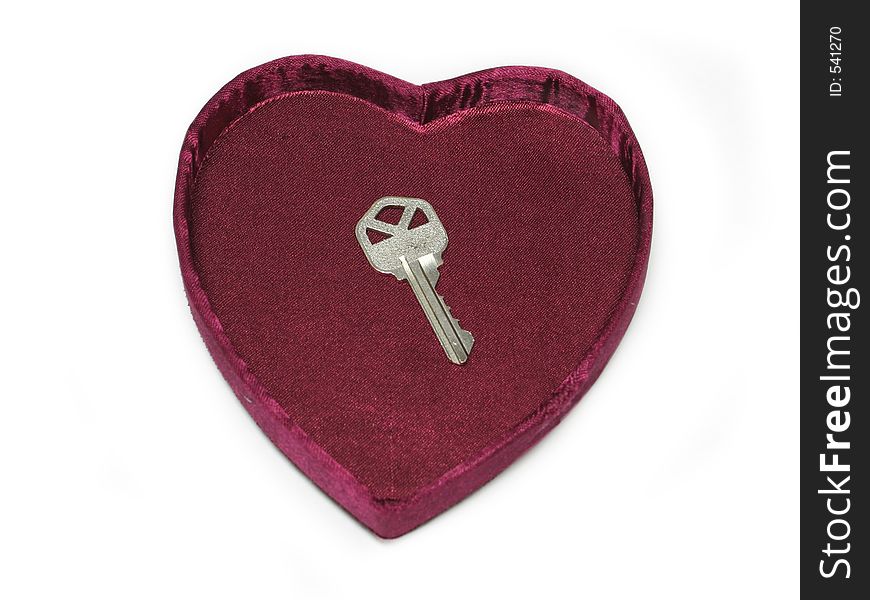 Close up of a silver key inside of a heart shaped box. Close up of a silver key inside of a heart shaped box