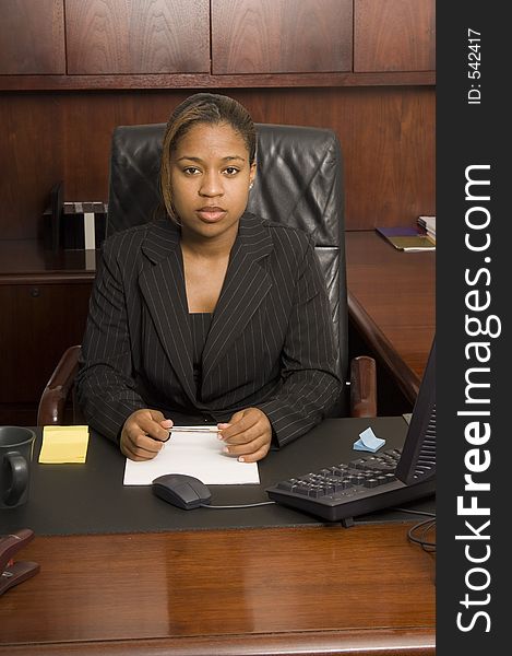 Young woman behind executive desk looking confident and ready for business. Young woman behind executive desk looking confident and ready for business