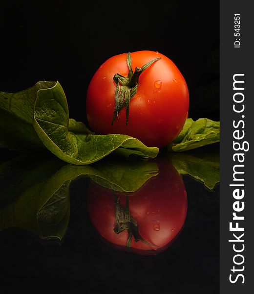 Tomato and salat on black and shine background. Tomato and salat on black and shine background