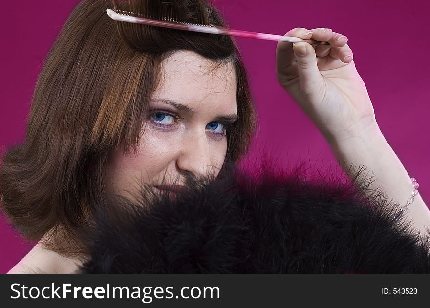 Young girl creating a hair style and black feathers on purple background