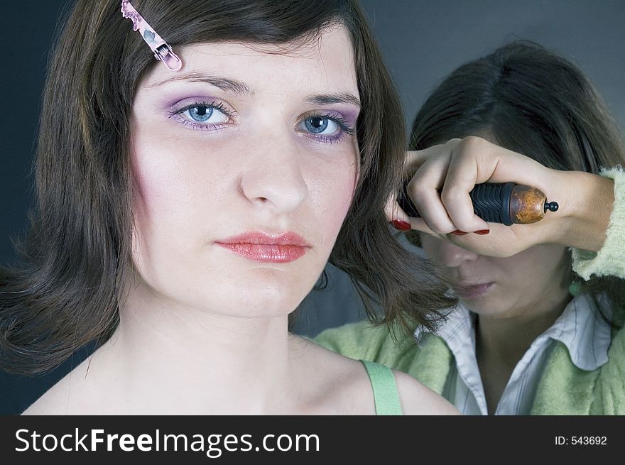 Young woman with great make-up having her hair brushed by a hair stylist. Young woman with great make-up having her hair brushed by a hair stylist