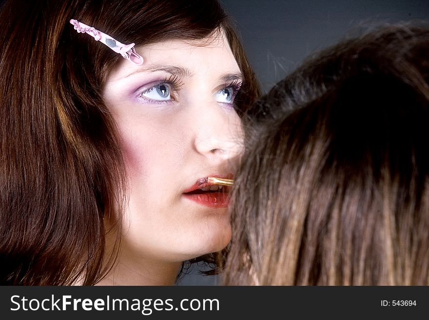 Young woman with great make-up having lipstick applied by her make-up artist. Young woman with great make-up having lipstick applied by her make-up artist