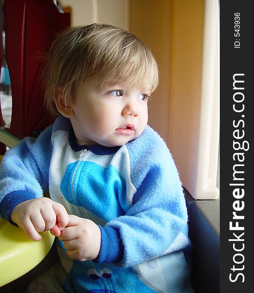 A young toddler watching the snow fall outside