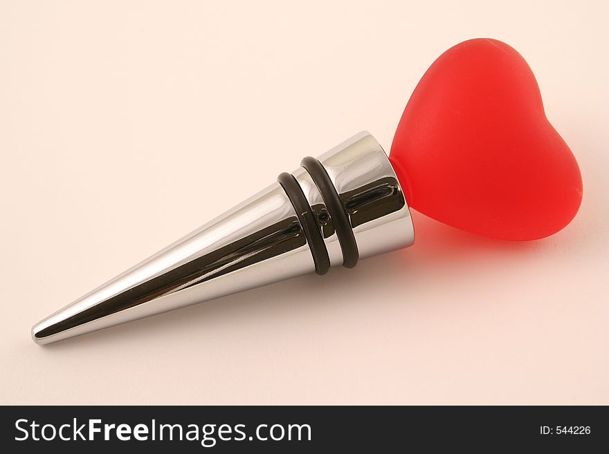 A chrome wine stopper decorated with a red heart. A chrome wine stopper decorated with a red heart