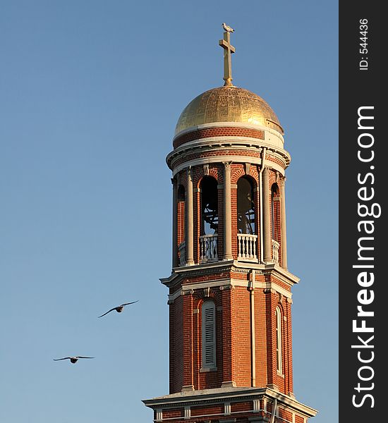 Birds flying by a church bell tower