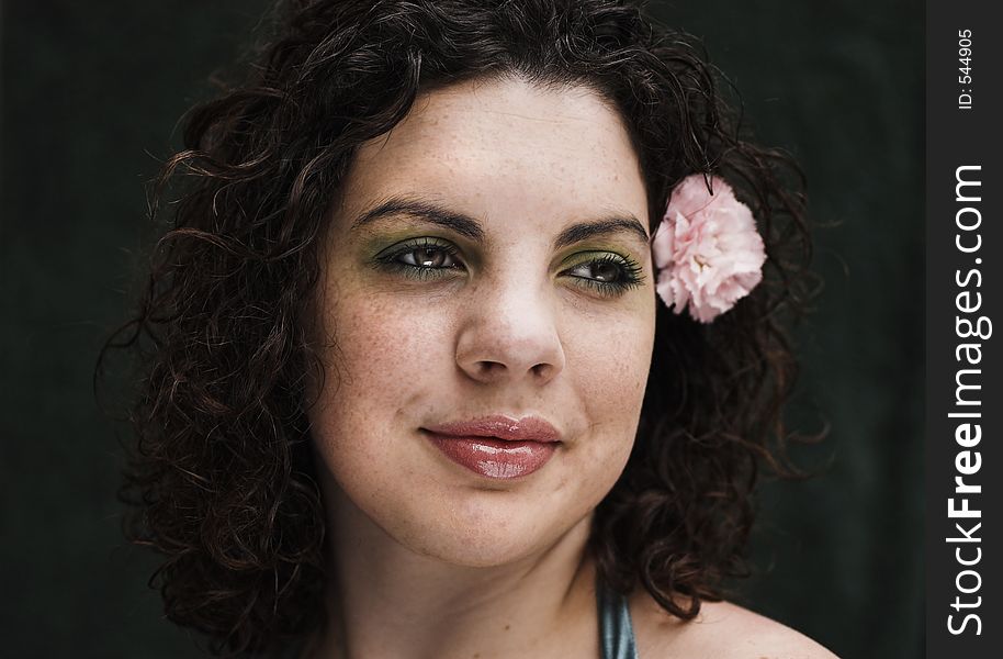 A young pretty teenager with a pink carnation in her hair. A young pretty teenager with a pink carnation in her hair.