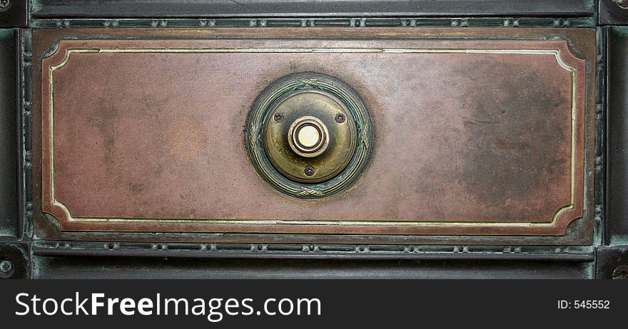 Image of an old fashioned door bell on a metal plate. Image of an old fashioned door bell on a metal plate