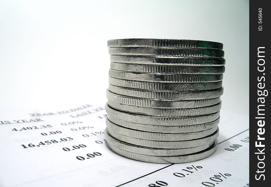 Coins on top of a financial report. Shallow depth of field. Focus on the coins. Coins on top of a financial report. Shallow depth of field. Focus on the coins.
