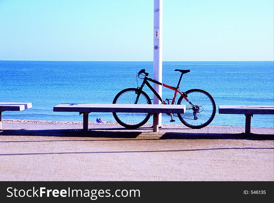 Parked bicycle and a men at rest on the beach in the background. Parked bicycle and a men at rest on the beach in the background