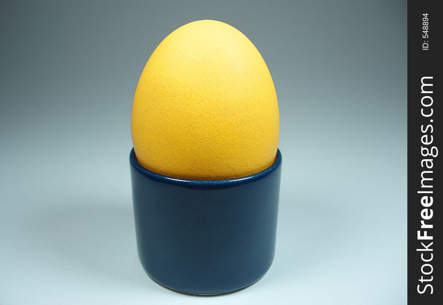 A yellow hen´s egg in a blue egg-cup. This could be part of the breakfast at Easter. A yellow hen´s egg in a blue egg-cup. This could be part of the breakfast at Easter.