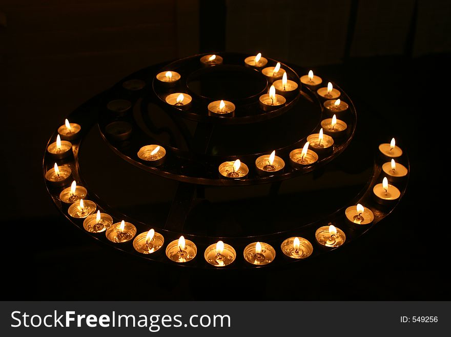 A concentric circle of candles gutters in a church at night. A concentric circle of candles gutters in a church at night