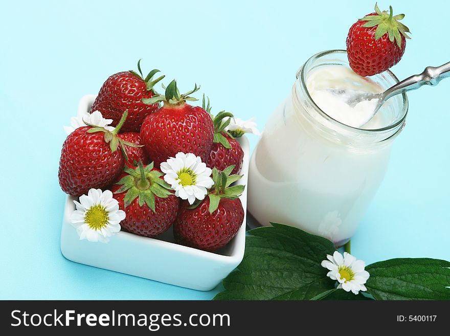 Closeup of open jar of organic yogurt and delicious strawberries with flowers. Closeup of open jar of organic yogurt and delicious strawberries with flowers.