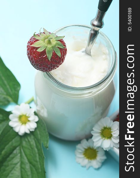 Closeup of open jar of organic yogurt and delicious strawberries with flowers. Closeup of open jar of organic yogurt and delicious strawberries with flowers.