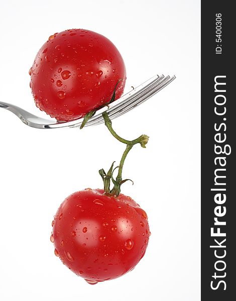 Two tomatoes dangling from a fork