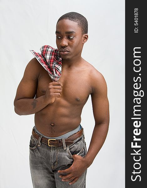 Young dark skinned handsome guy standing like a macho with a hand hanging from his pocket and the other holding a checkered shirt over his shoulder and showing his six pack, isolated. Young dark skinned handsome guy standing like a macho with a hand hanging from his pocket and the other holding a checkered shirt over his shoulder and showing his six pack, isolated.