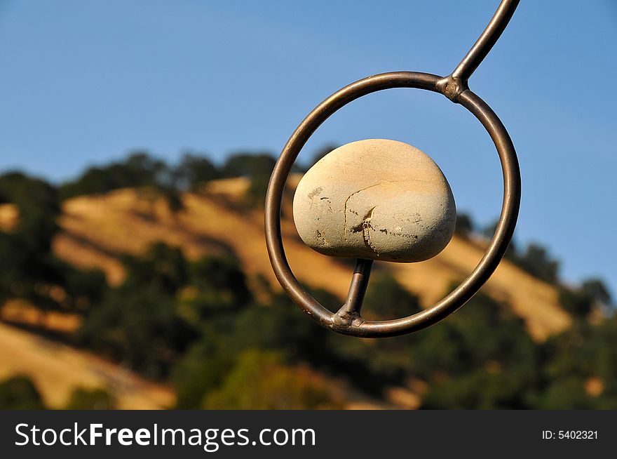 Closeup of Stone and Metal Sculpture with a background view of Green Valley Foothills