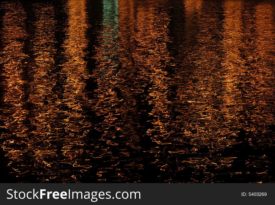 Orange lights reflecting on gently moving water. Orange lights reflecting on gently moving water