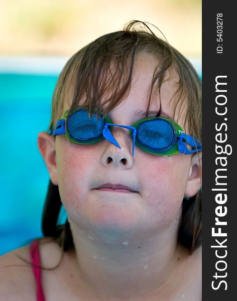 A young girl with swimming goggles in an inflatable pool