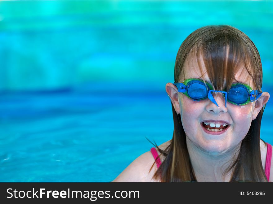 A young girl with swimming goggles in an inflatable pool with room on right for type