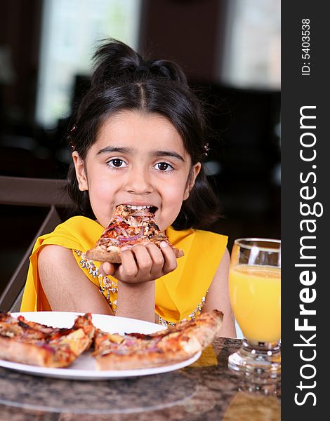 Little girl in east indian clothes holding a pizza slice. Little girl in east indian clothes holding a pizza slice