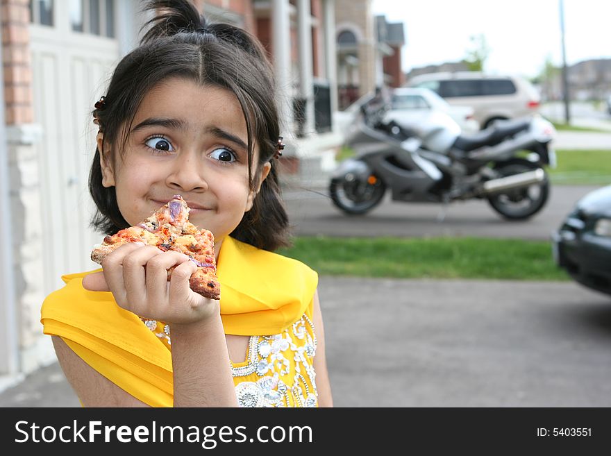 Little girl in east indian clothes holding a pizza slice. Little girl in east indian clothes holding a pizza slice