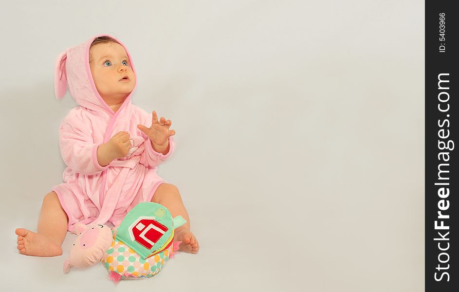 8 months old girl sitting after a bath wearing pink rabbit style bathrobe. 8 months old girl sitting after a bath wearing pink rabbit style bathrobe