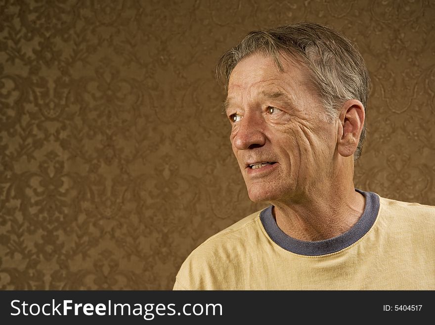 Man with a craggy face wearing a yellow shirt against a gold background with copy space. Man with a craggy face wearing a yellow shirt against a gold background with copy space