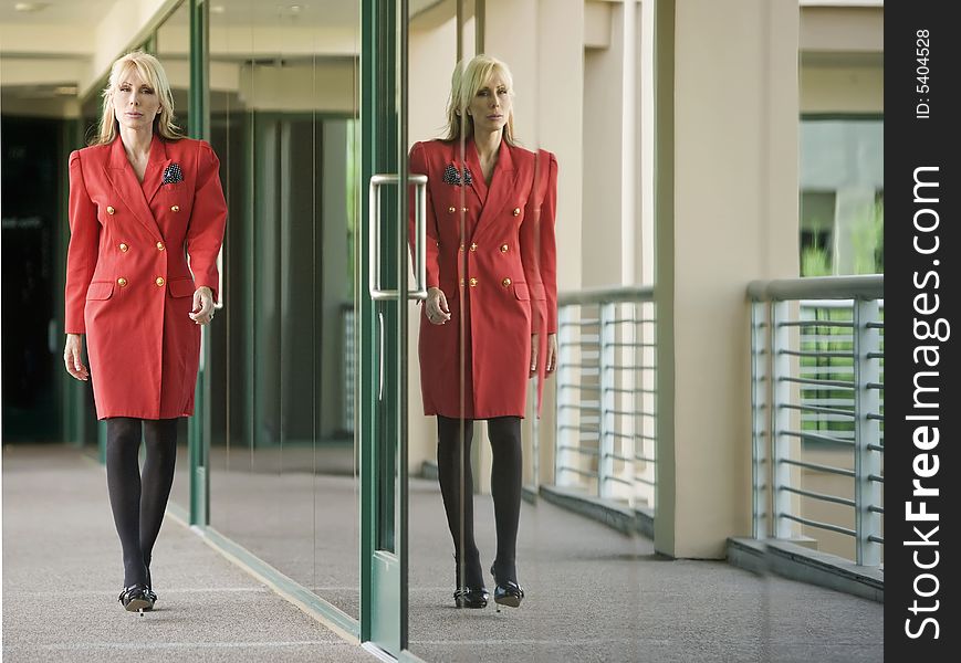 Businesswoman in a red suit reflected in building glass. Businesswoman in a red suit reflected in building glass