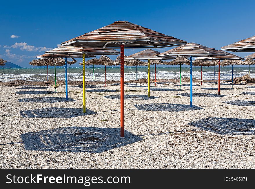 Set of beach umbrellas on sand making shadows under the blue clear sky in hot day. Set of beach umbrellas on sand making shadows under the blue clear sky in hot day