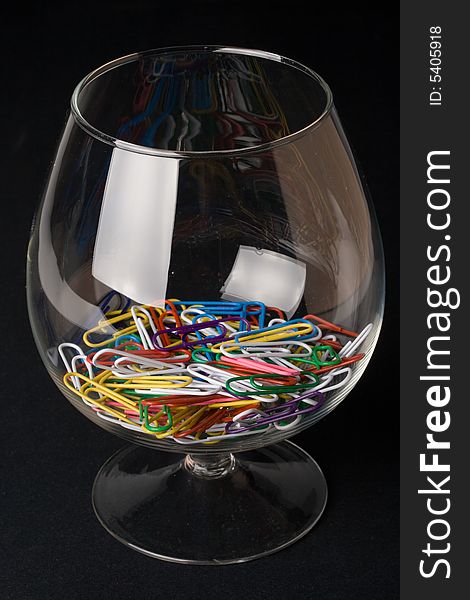 Colored paperclips in a glass on a black background. Close up. Selective focus.